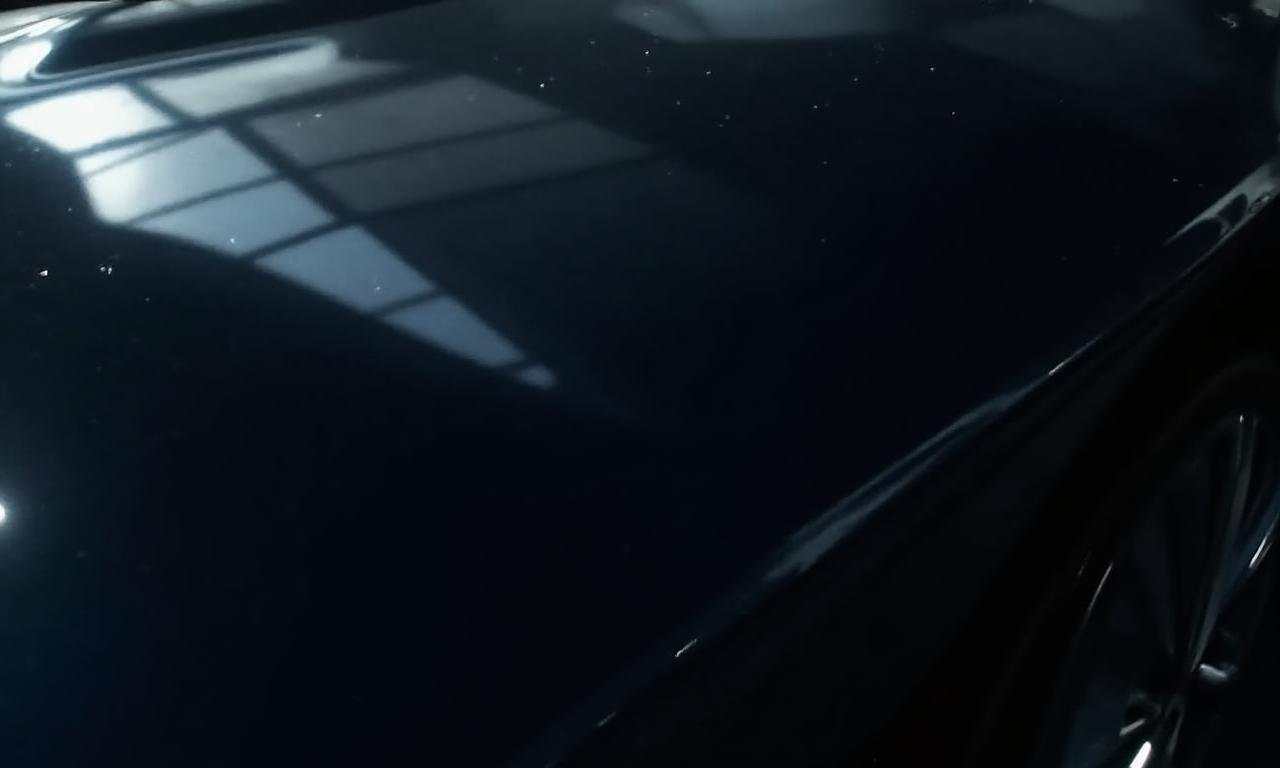 A close-up of a perfectly detailed glossy black car reflecting clean lights.